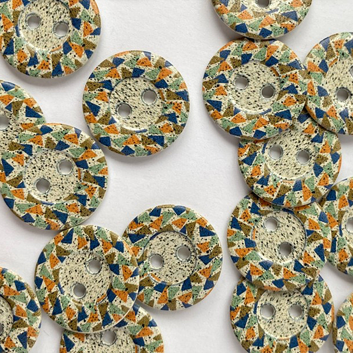 Cream metal button with speckled centre and raised edge.