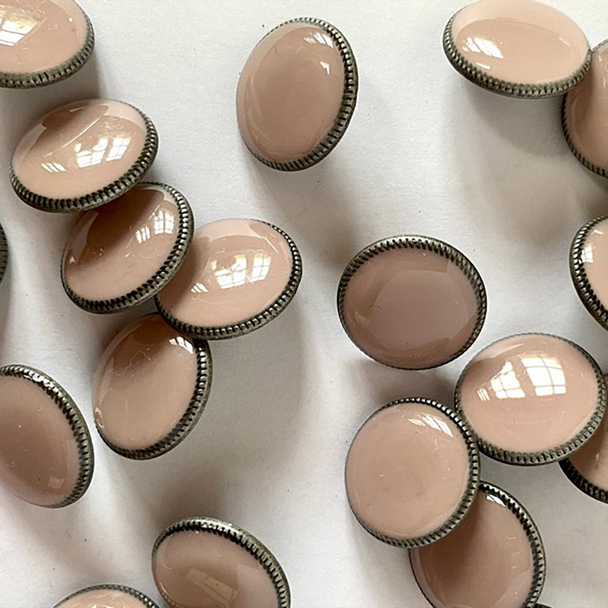 Glossy dusty pink button on dark grey metal base with shank