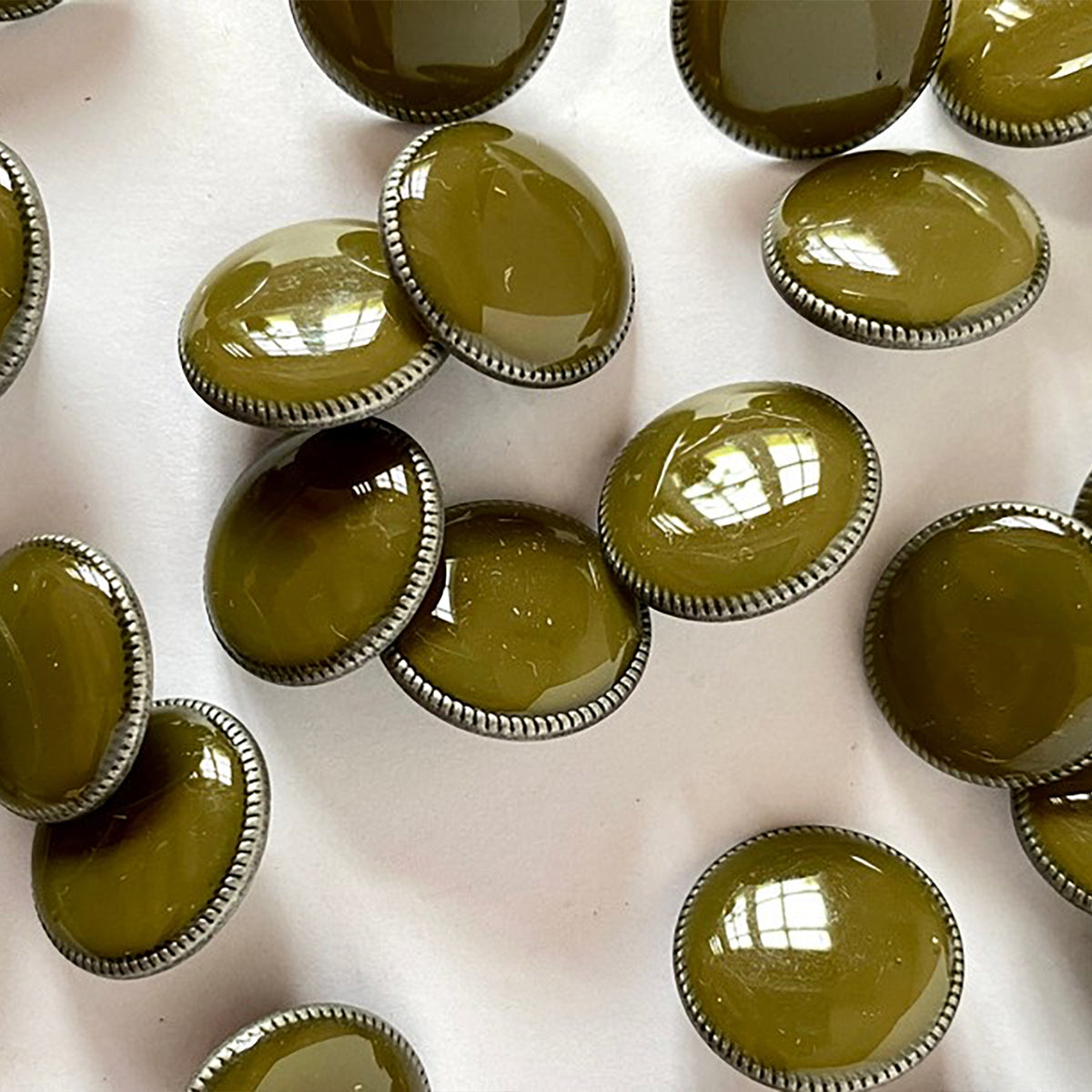 Glossy green khaki button on dark grey metal base with shank